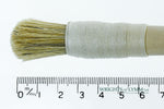 A short, string-bound gesso brush for applying gesso in gilding projects